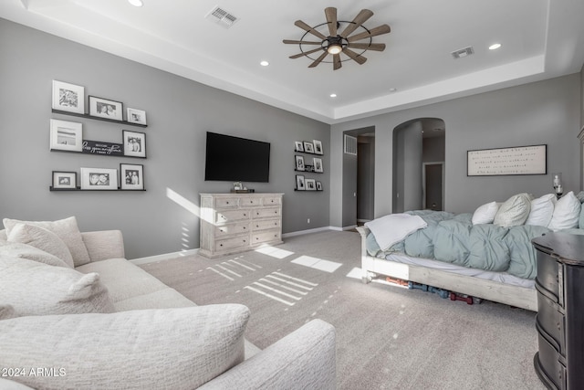 bedroom with a raised ceiling and light colored carpet