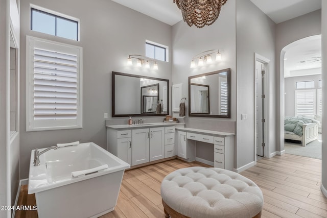 bathroom featuring vanity, hardwood / wood-style flooring, a bathing tub, and a towering ceiling