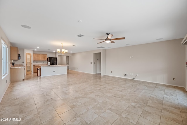 unfurnished living room featuring ceiling fan with notable chandelier