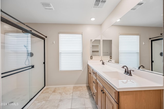 bathroom with a shower with door, vanity, and tile patterned flooring