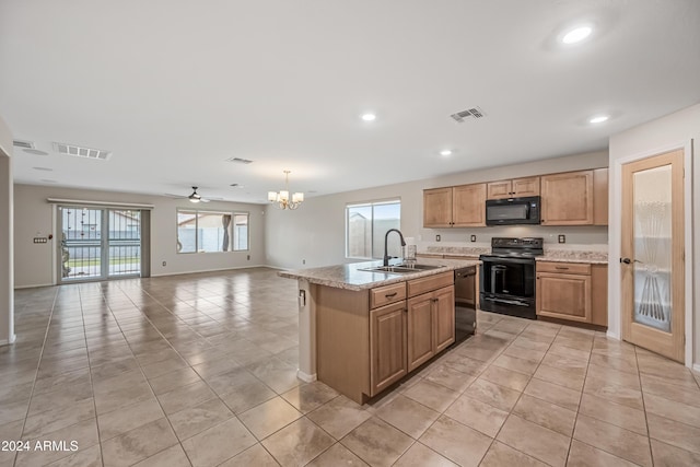 kitchen featuring light stone countertops, ceiling fan with notable chandelier, sink, black appliances, and a center island with sink