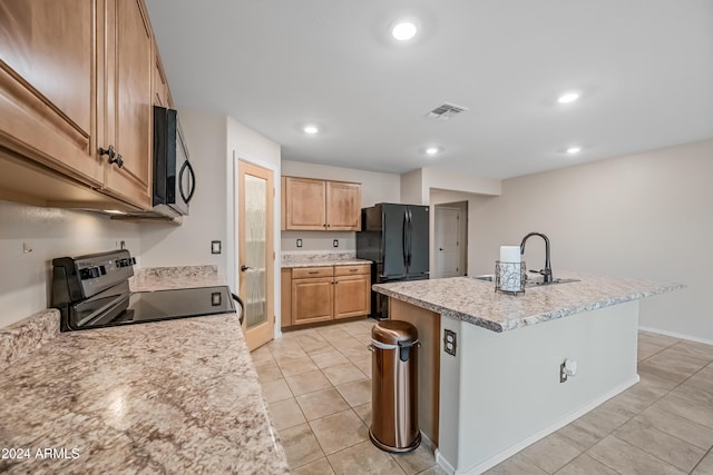 kitchen with black appliances, light tile patterned flooring, a center island with sink, and sink