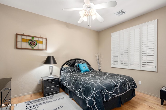 bedroom featuring a ceiling fan, baseboards, visible vents, and wood finished floors