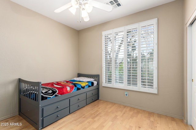 bedroom featuring a ceiling fan, baseboards, visible vents, and wood finished floors