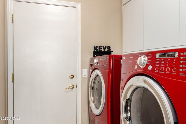 clothes washing area featuring cabinet space and separate washer and dryer