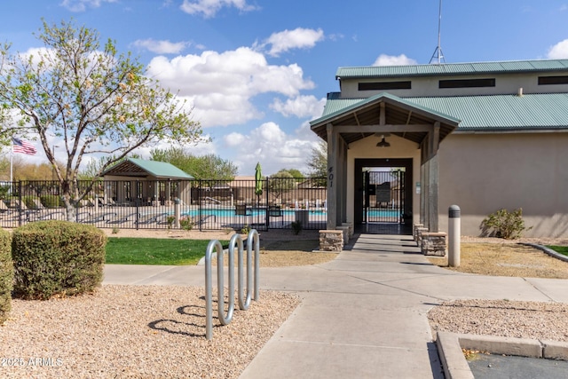 property entrance with metal roof, fence, a community pool, and stucco siding