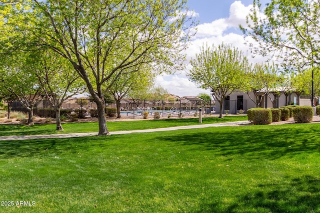 surrounding community with fence, a swimming pool, and a lawn