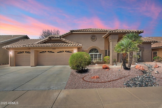 mediterranean / spanish home featuring stucco siding, an attached garage, driveway, and a tile roof