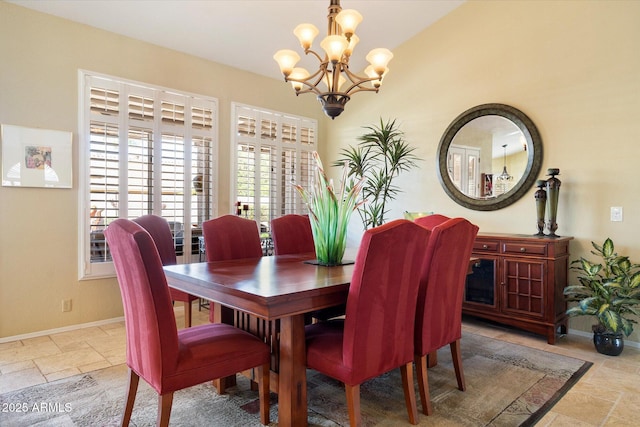 dining room featuring stone tile floors, a notable chandelier, and baseboards