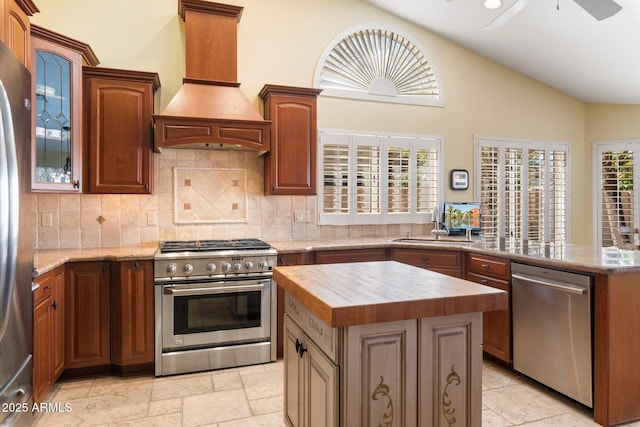 kitchen with premium range hood, wood counters, tasteful backsplash, appliances with stainless steel finishes, and vaulted ceiling