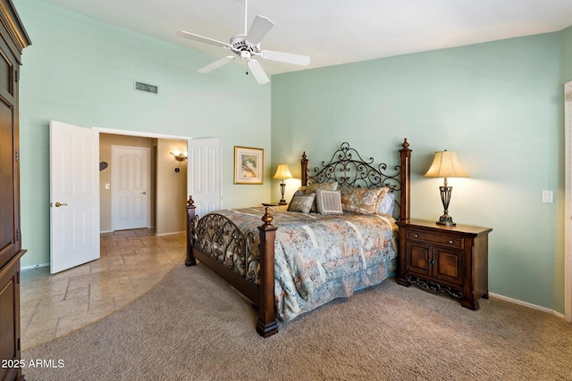 bedroom with visible vents, a ceiling fan, stone tile flooring, a high ceiling, and baseboards