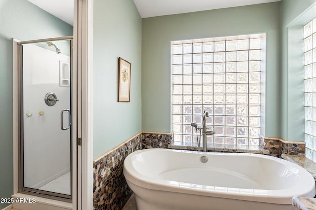 bathroom with a wainscoted wall, a freestanding bath, tile walls, and a shower stall