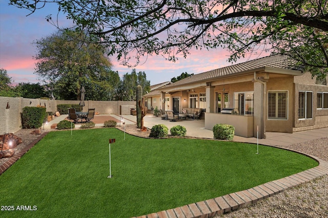 yard at dusk with a fenced backyard, outdoor lounge area, and a patio area