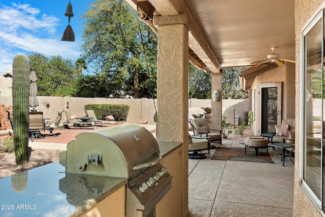 view of patio / terrace with grilling area, an outdoor kitchen, a fenced backyard, and a ceiling fan