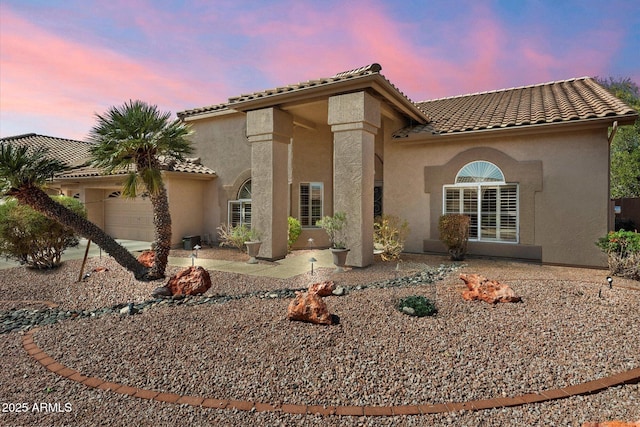 exterior space featuring stucco siding, an attached garage, and a tile roof