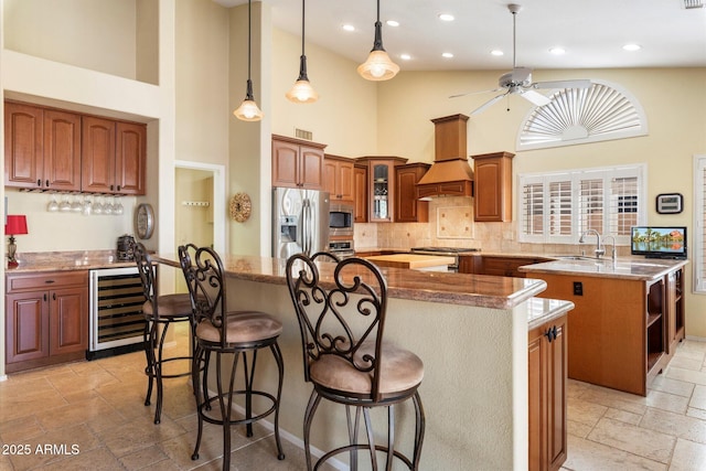 kitchen featuring a kitchen island, wine cooler, custom range hood, stone tile floors, and stainless steel appliances