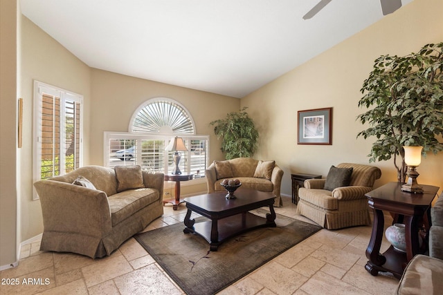 living area featuring baseboards, lofted ceiling, and stone tile floors