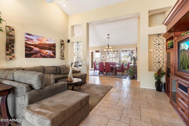 living area with baseboards, high vaulted ceiling, stone tile floors, and a chandelier