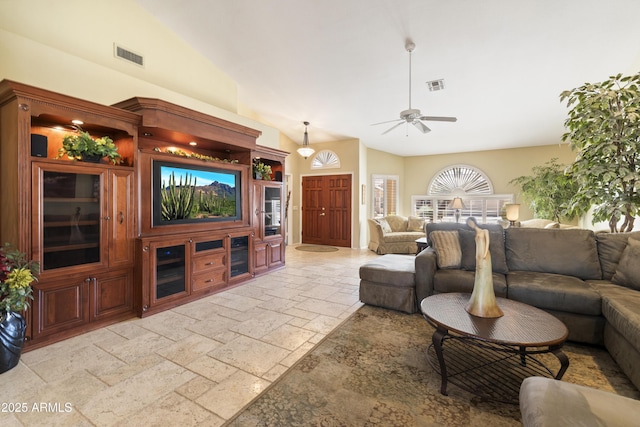 living room with stone tile floors, visible vents, ceiling fan, and vaulted ceiling