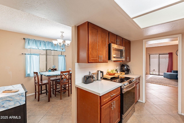 7764 N 19th Dr, Phoenix, AZ 85021 - kitchen with light tile patterned floors, a notable chandelier, stainless steel appliances, and backsplash
