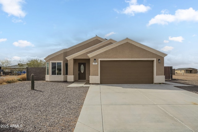 ranch-style home featuring concrete driveway, fence, an attached garage, and stucco siding