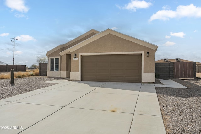 view of front of house featuring driveway, an attached garage, fence, and stucco siding