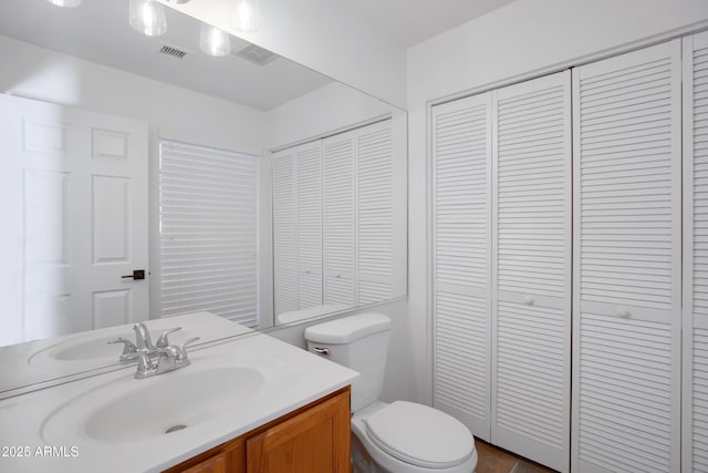 bathroom with a closet, visible vents, toilet, and vanity