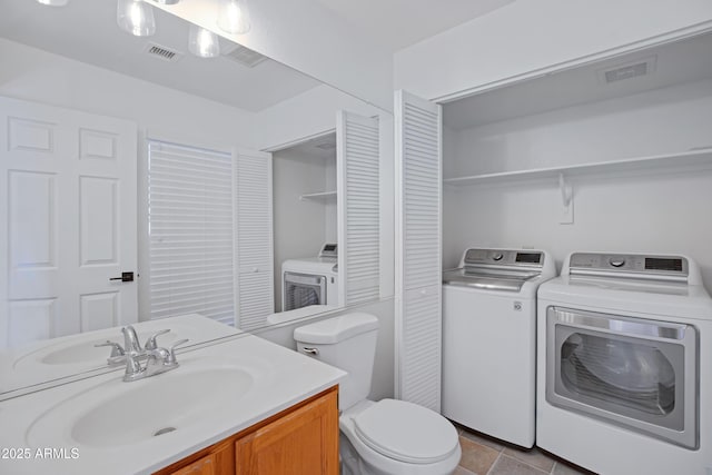 bathroom with visible vents, washer and dryer, toilet, and vanity