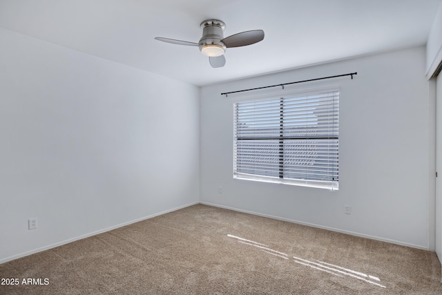 spare room with carpet flooring, a ceiling fan, and baseboards