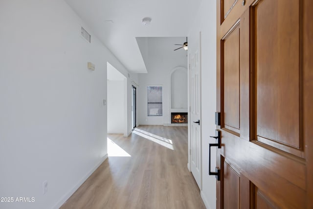 hall featuring visible vents, baseboards, and light wood-style flooring