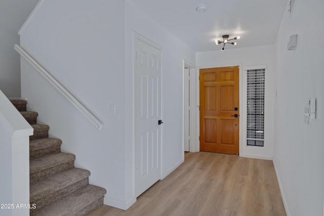 entryway featuring light wood-type flooring, baseboards, and stairway