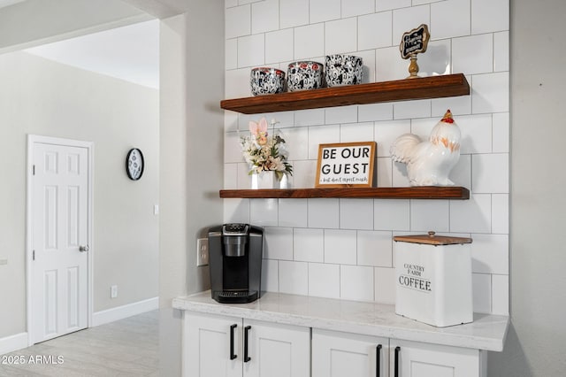 bar featuring decorative backsplash, baseboards, and light wood-type flooring