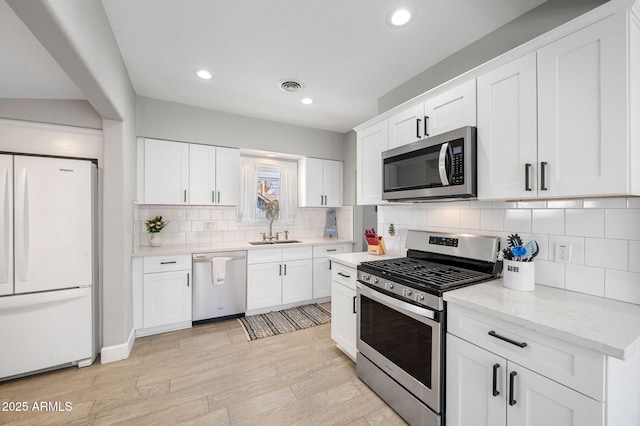 kitchen with visible vents, a sink, tasteful backsplash, white cabinetry, and appliances with stainless steel finishes