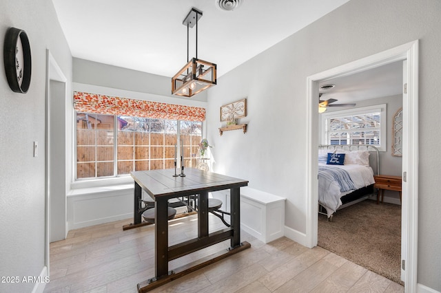 dining space with light wood-type flooring, plenty of natural light, baseboards, and ceiling fan with notable chandelier