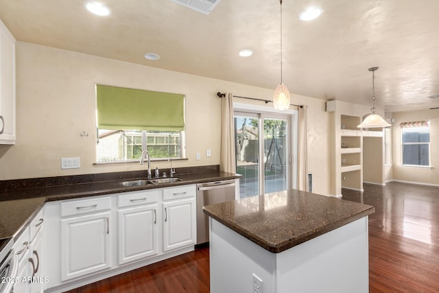 kitchen with sink, white cabinetry, decorative light fixtures, stainless steel dishwasher, and a kitchen island