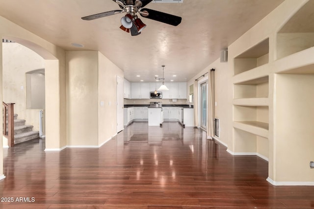 unfurnished living room with dark hardwood / wood-style floors, built in features, and ceiling fan