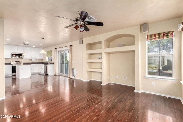 unfurnished living room with ceiling fan, dark hardwood / wood-style floors, and built in features