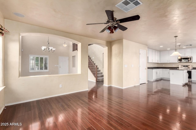 unfurnished living room featuring dark hardwood / wood-style flooring and ceiling fan with notable chandelier