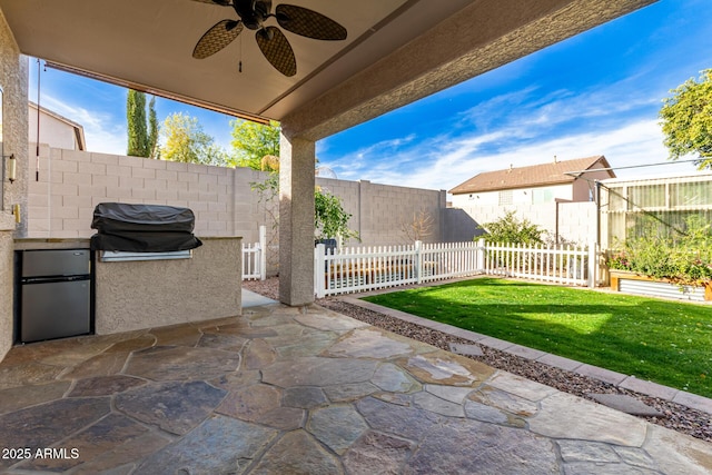 view of patio / terrace with area for grilling, ceiling fan, and exterior kitchen