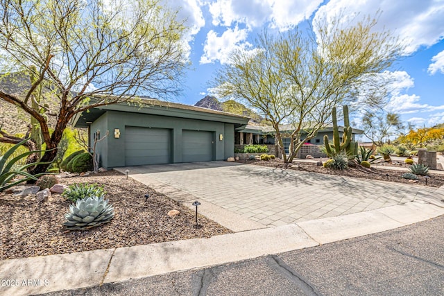 ranch-style home with an attached garage, decorative driveway, and stucco siding
