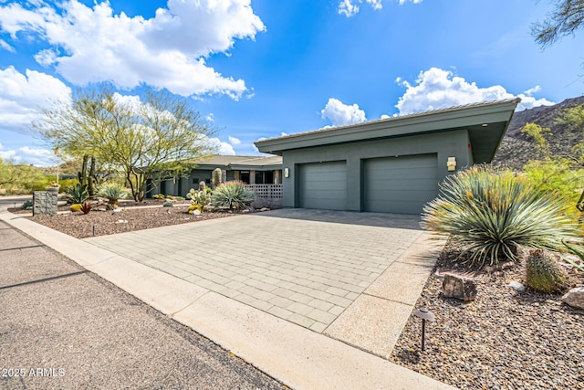 view of front of property featuring stucco siding, decorative driveway, covered porch, and a garage