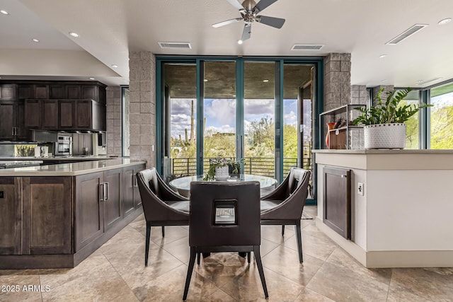 dining space with a wall of windows, visible vents, ceiling fan, and light tile patterned floors