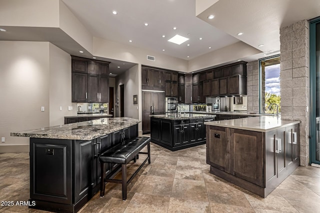 kitchen featuring oven, a large island, light stone countertops, visible vents, and recessed lighting