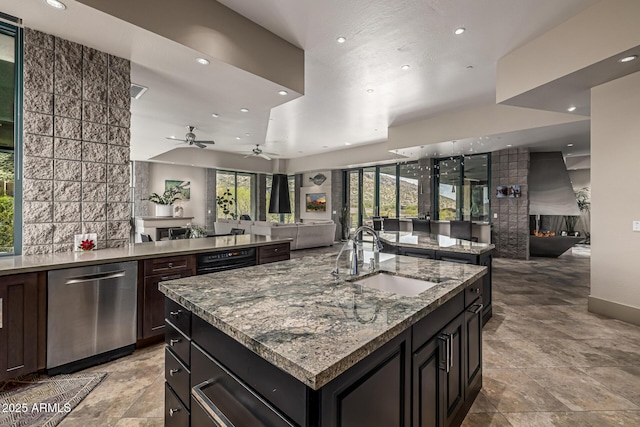 kitchen featuring dishwasher, open floor plan, a sink, and a center island with sink