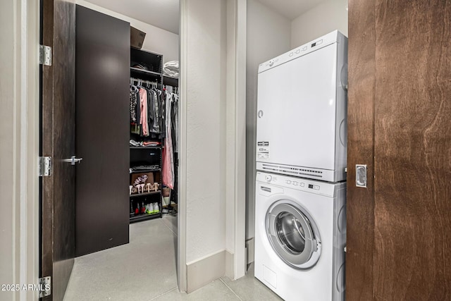 laundry area with baseboards, stacked washing maching and dryer, and laundry area