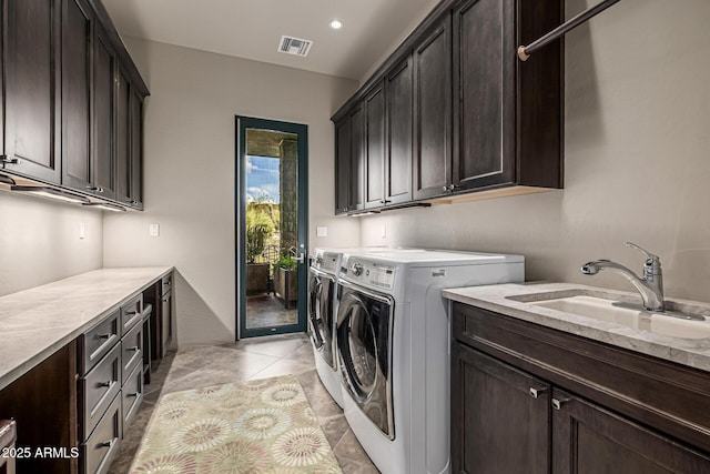 laundry area featuring visible vents, light tile patterned floors, a sink, washer and dryer, and cabinet space