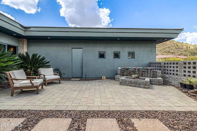 back of house featuring a fire pit, a patio, and stucco siding