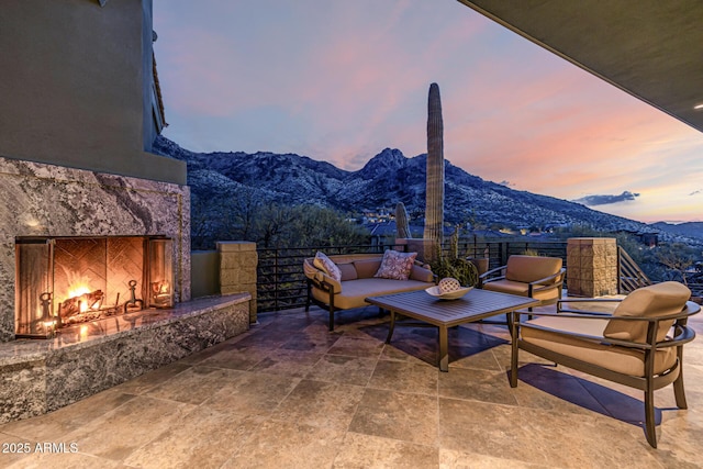 patio terrace at dusk featuring a mountain view and an outdoor living space with a fireplace
