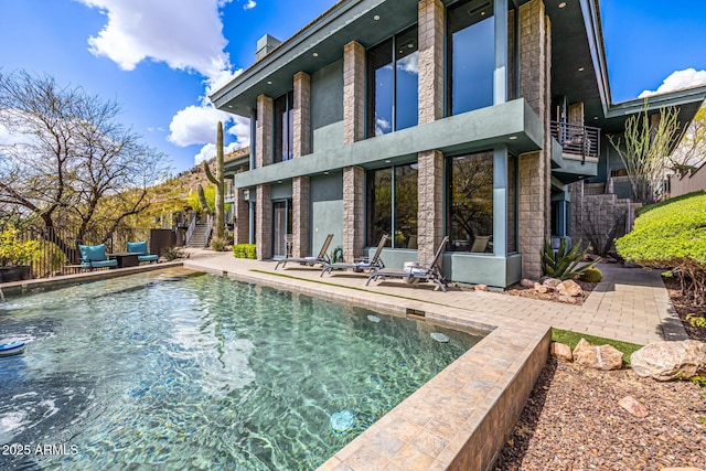 rear view of house featuring a patio, a balcony, and a fenced in pool