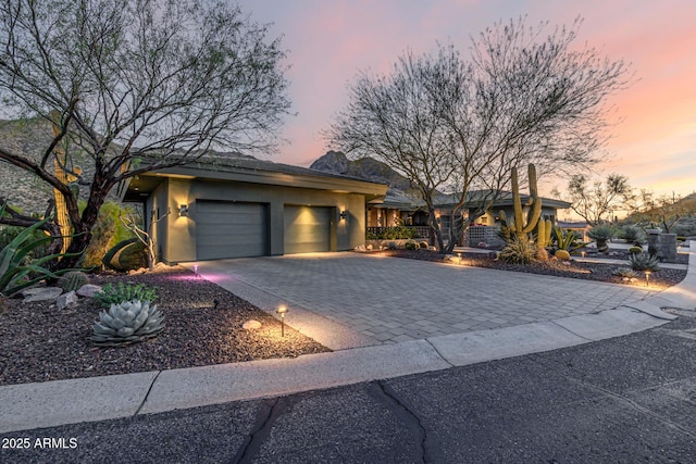 view of front of home with a garage, decorative driveway, and stucco siding